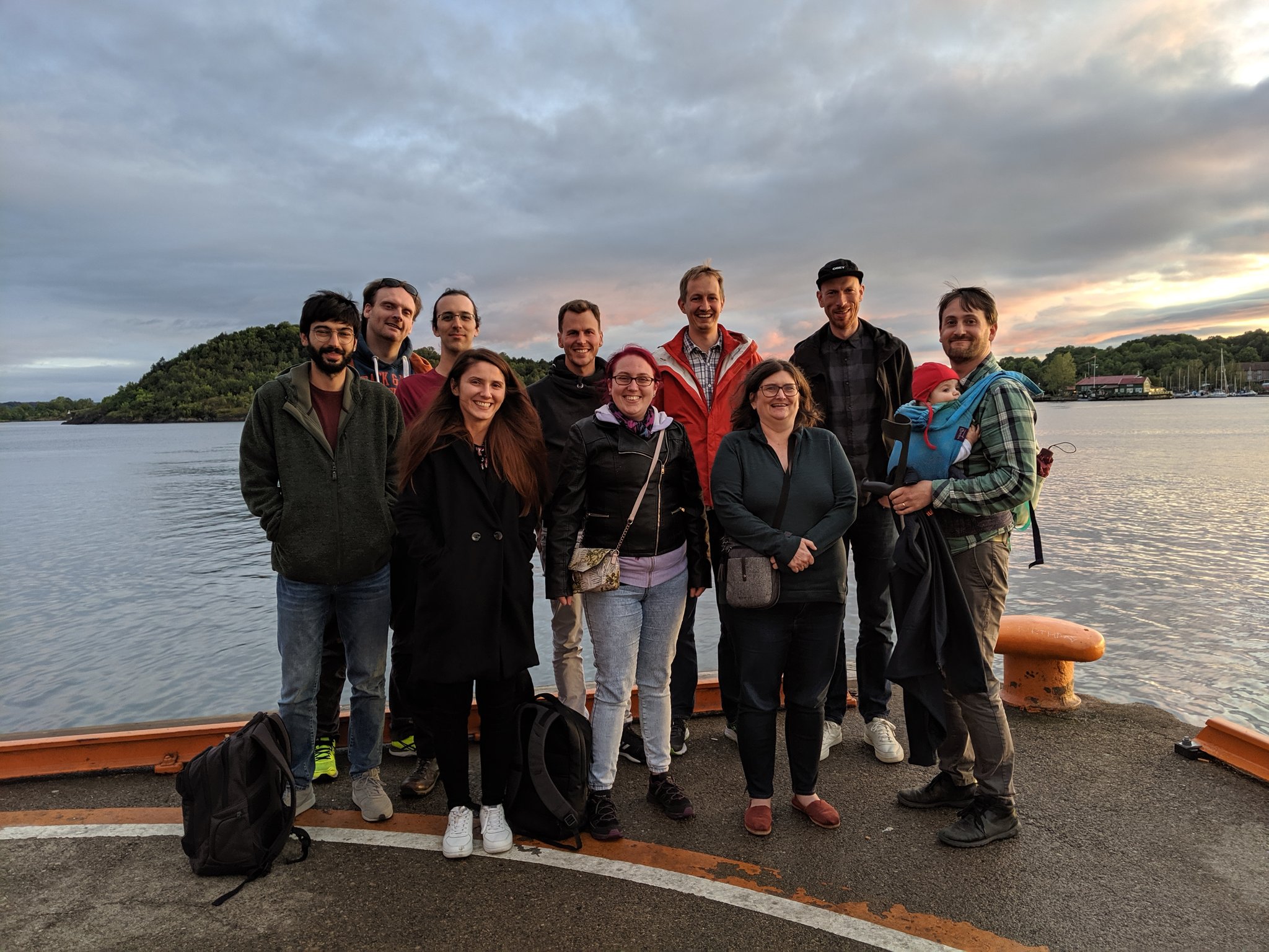 Ten team members standing in front of a lake smiling at the camera